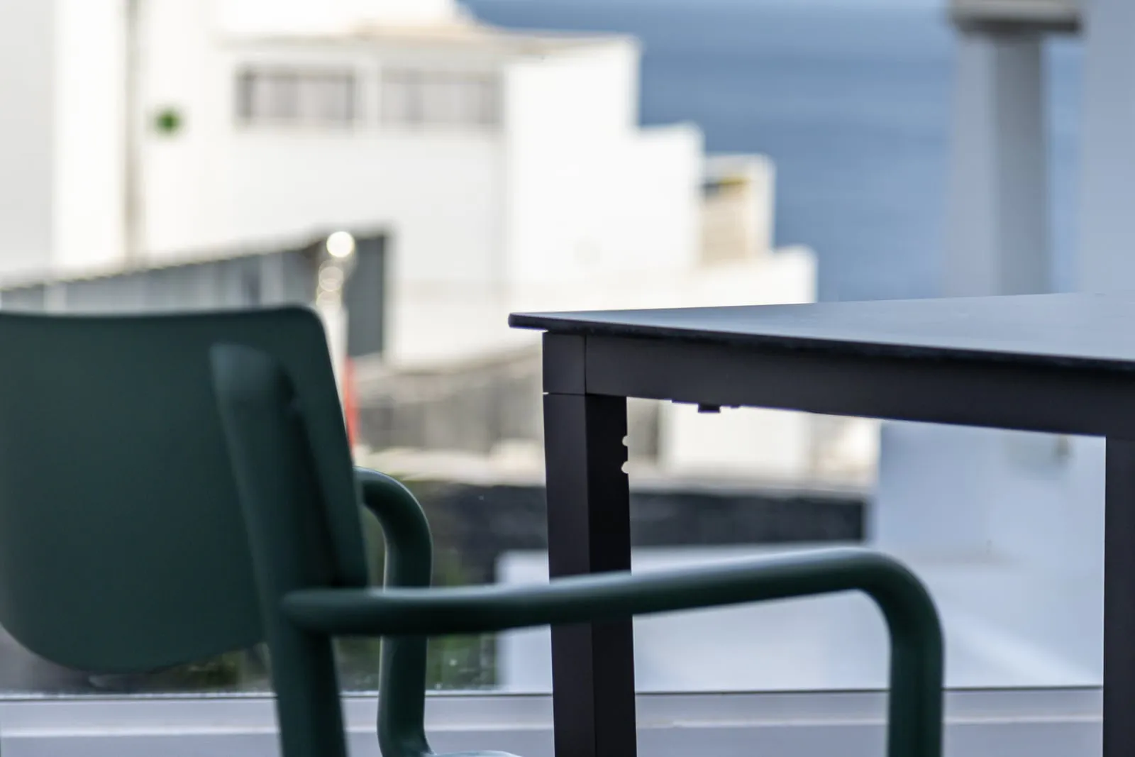 The terrace of apartment 118: a green chair, a small table and the sea beyond