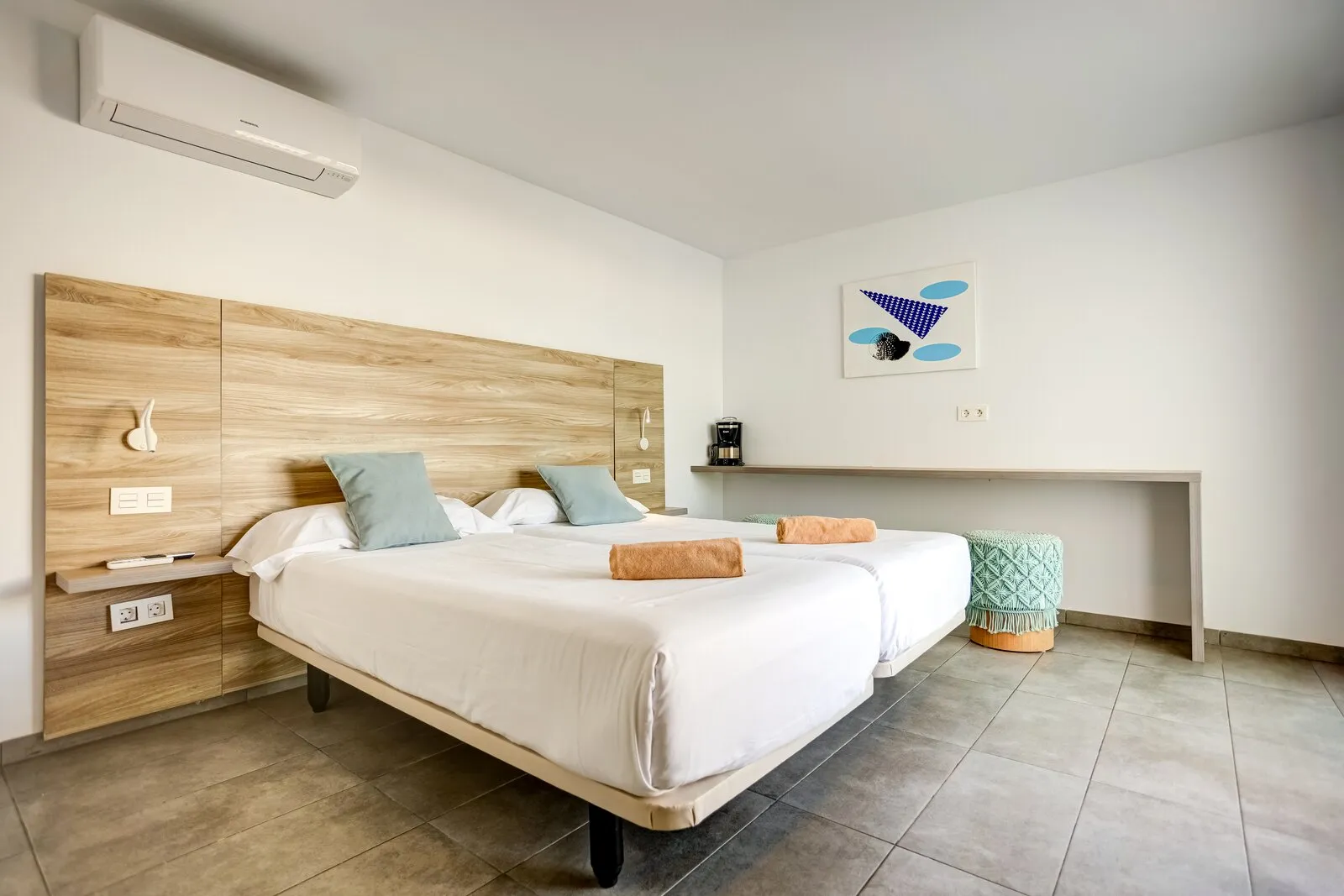 Apartment 206 with two beds beneath the timber headboard and a long desk along the opposite wall