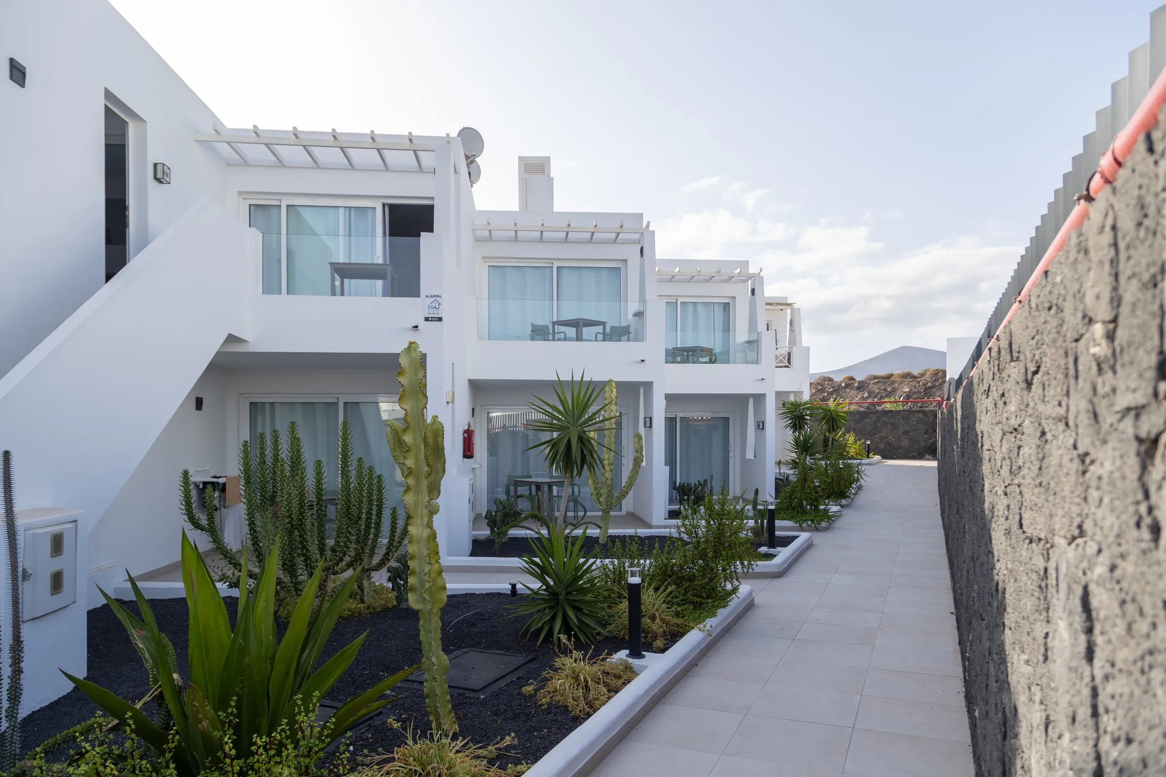 The upper-floor apartments above a cactus garden, with the volcanic ridge at the end of the walkway